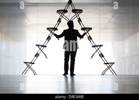 Businessman arranging office chair installation art Stock Photo