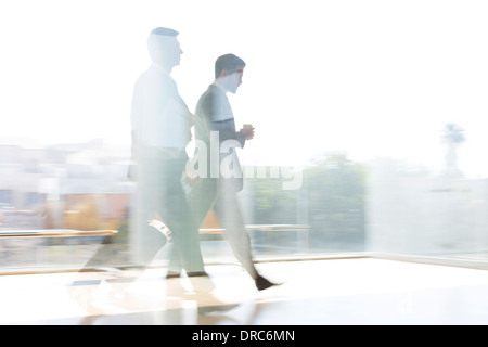Businessmen walking in sunny airport corridor Stock Photo