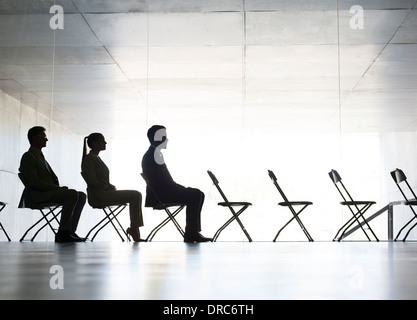 Business people sitting in office chairs in a row Stock Photo