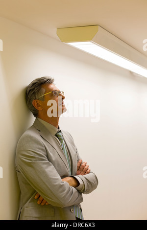 Businessman leaning against office wall Stock Photo