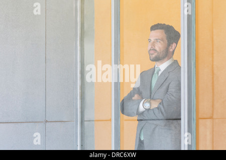 Businessman standing at office window Stock Photo