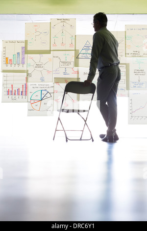 Businessman viewing charts and graphs on office wall Stock Photo