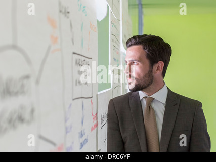 Businessman looking out hole in office window Stock Photo