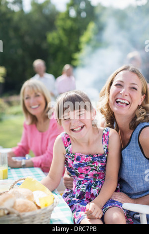 Mother and daughter laughing at table in backyard Stock Photo