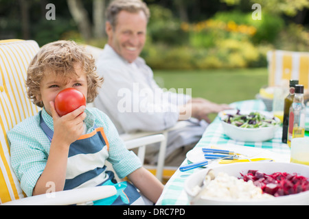 Boy playing with food at table in backyard Stock Photo