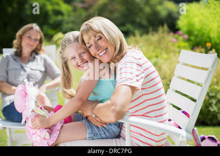 Grandmother and granddaughter hugging in backyard Stock Photo