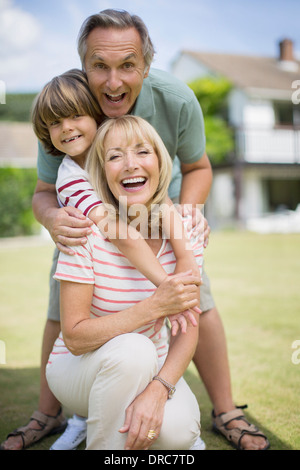 Grandparents and grandson hugging outdoors Stock Photo