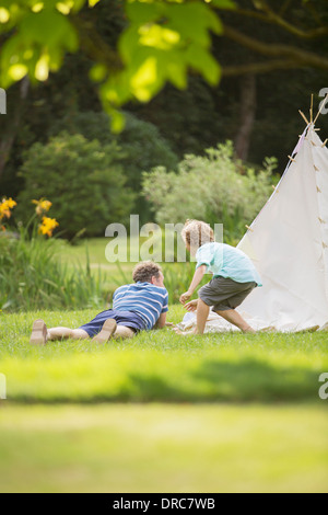 Father and son laying outside teepee Stock Photo