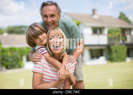 Grandparents and grandson hugging in backyard Stock Photo
