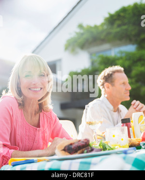 Smiling woman at table in backyard Stock Photo