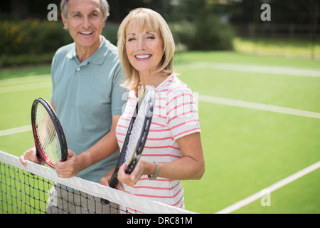 Couple smiling on tennis court Stock Photo