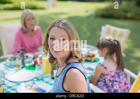 Multi-generation family eating at table in backyard Stock Photo