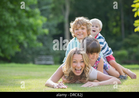 Children laying on mother in grass Stock Photo