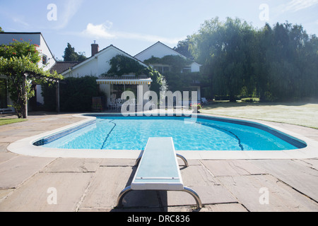 Diving board at the edge of swimming pool Stock Photo