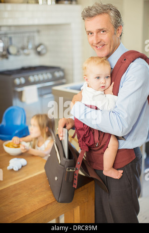 Businessman carrying baby in kitchen Stock Photo