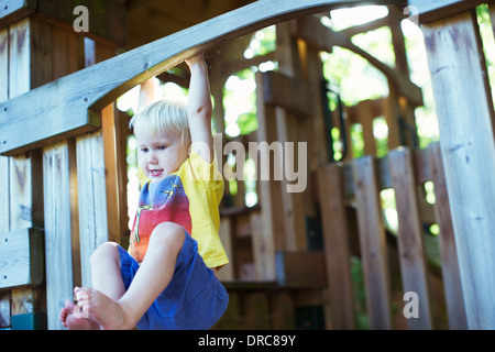 Young Caucasian boy hanging on monkey bars in park on ...