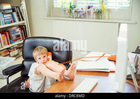 Boy talking on phone in home office Stock Photo