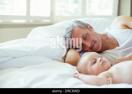 Father and baby laying on bed Stock Photo