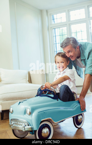 Father pushing son in toy car Stock Photo