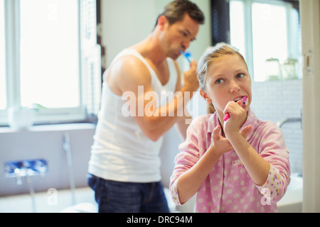 Father and daughter brushing teeth in bathroom Stock Photo