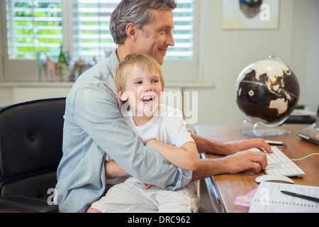 Father holding son and using computer Stock Photo