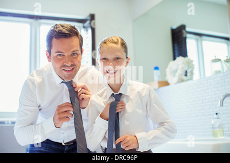 Father and daughter adjusting ties in bathroom Stock Photo