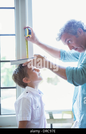 Father measuring son's height on wall Stock Photo