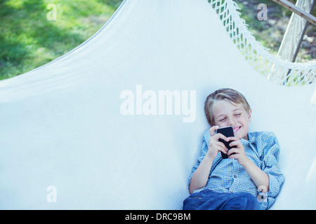 Boy using cell phone in hammock Stock Photo