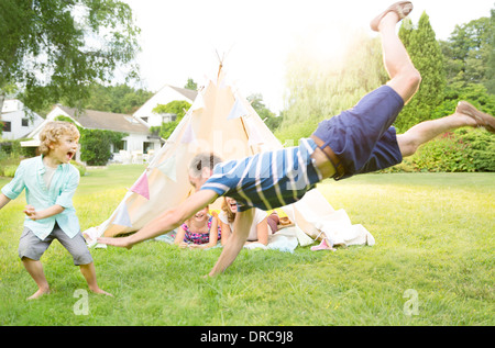 Family playing outside teepee in backyard Stock Photo