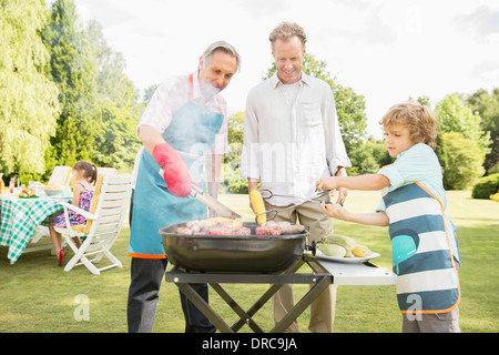 Men grilling meat on barbecue in backyard Stock Photo