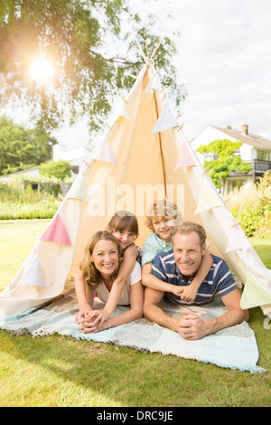 Family relaxing in teepee in backyard Stock Photo