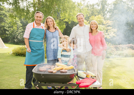 Multi-generation family standing at barbecue in backyard Stock Photo