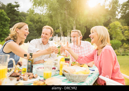 Couples toasting wine glasses at table in backyard Stock Photo