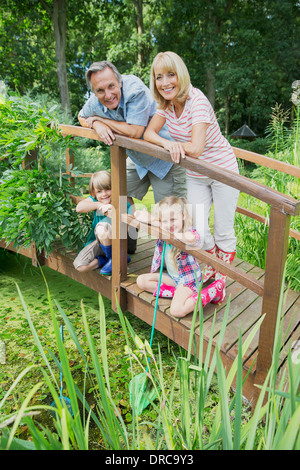 Grandparents and grandchildren smiling on wooden footbridge Stock Photo