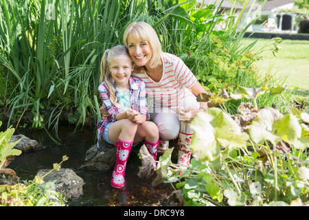 Grandmother and granddaughter smiling by pond Stock Photo