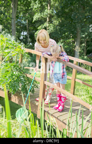 Grandmother and granddaughter fishing on wooden footbridge Stock Photo