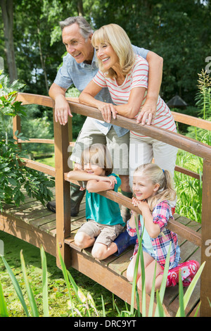 Grandparents and grandchildren smiling on wooden footbridge Stock Photo