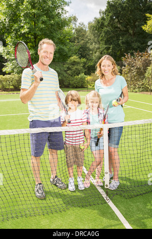 Family smiling together on grass tennis court Stock Photo