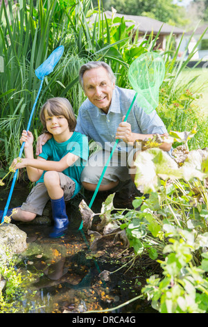 Grandfather and grandson fishing in pond Stock Photo