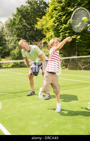 Father and son playing tennis on grass court Stock Photo