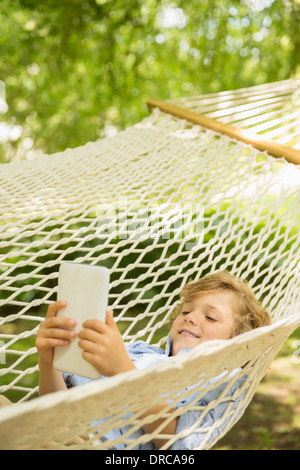 Boy using digital tablet in hammock Stock Photo