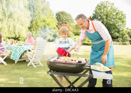 Grandfather and grandson grilling meat and corn on barbecue Stock Photo