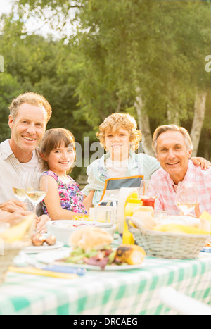 Multi-generation family eating lunch at table in backyard Stock Photo