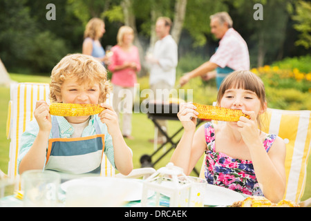 Children eating at table in backyard Stock Photo