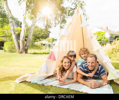 Family relaxing in teepee in backyard Stock Photo