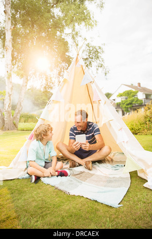 Father and son using digital tablet in teepee in backyard Stock Photo