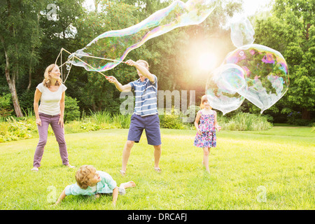 Family playing with large bubbles in backyard Stock Photo