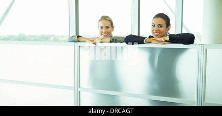 Smiling businesswomen leaning against half wall in office Stock Photo
