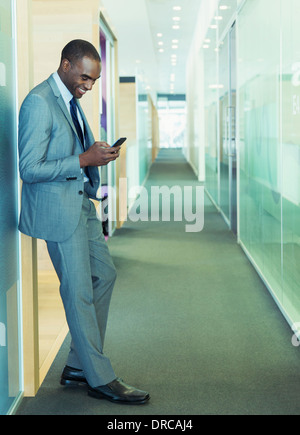 Businessman using cell phone in office corridor Stock Photo