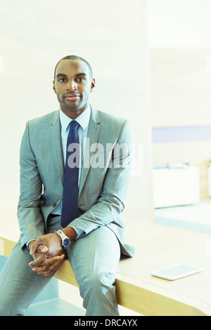 Businessman sitting on desk in office Stock Photo